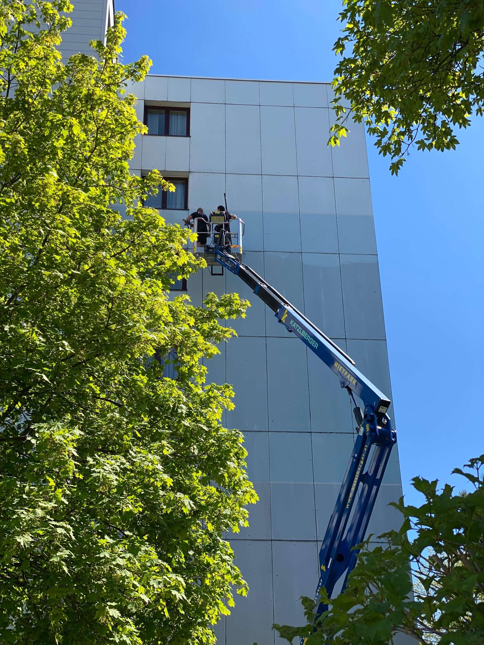 Strahlend saubere Fassade nach der Algenentfernung an einem großen Wohngebäude im Innviertel